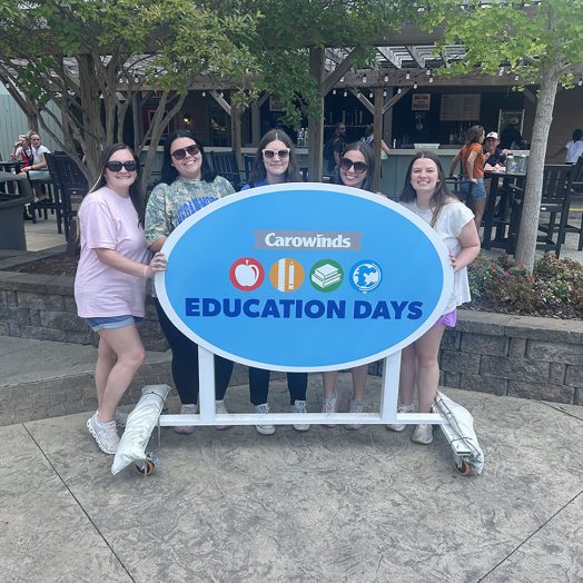 Group of people pose for photo in front of sign outdoors