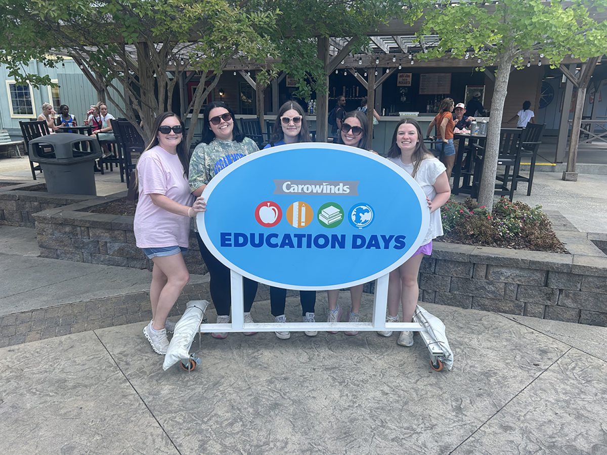 Group of people pose for photo in front of sign outdoors