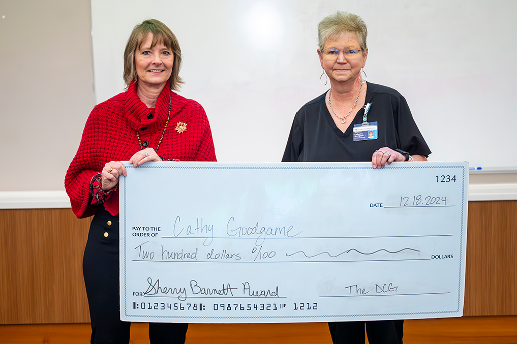 former dean of Dental College of Georgia holds oversized check with another woman