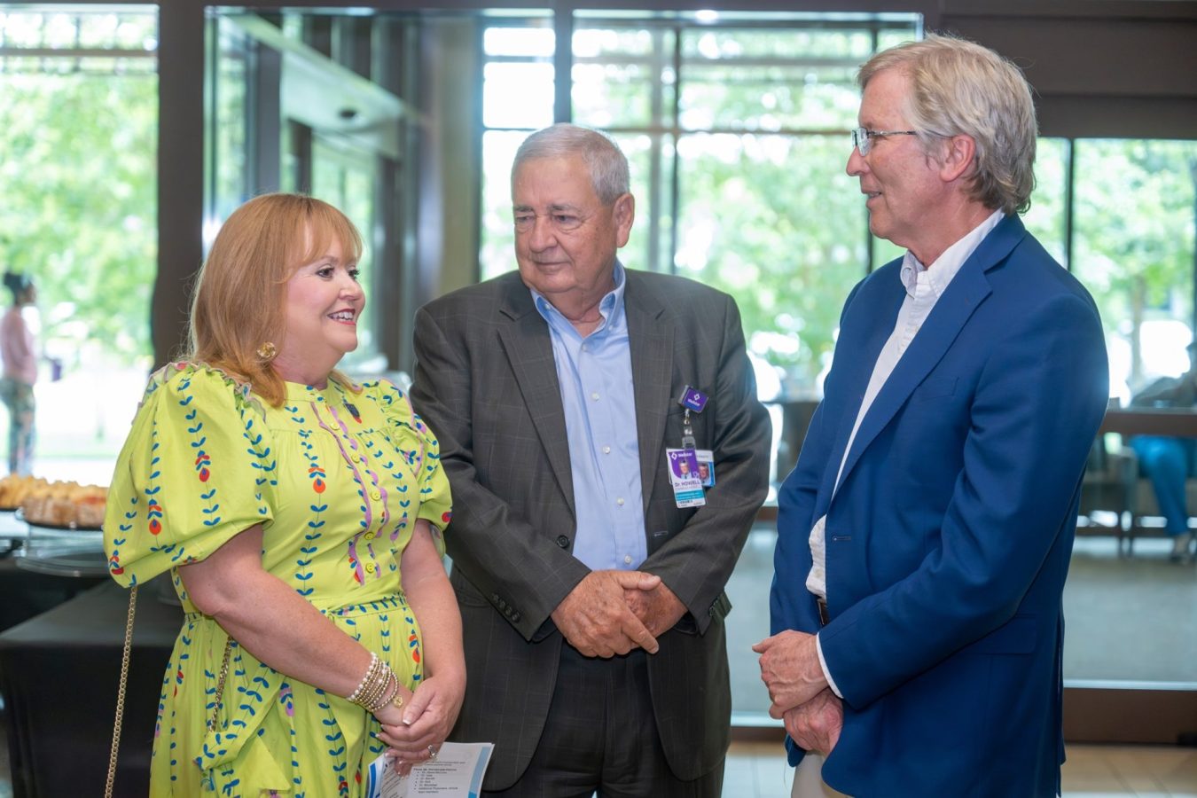In this photo, you see one female and two men standing and talking.