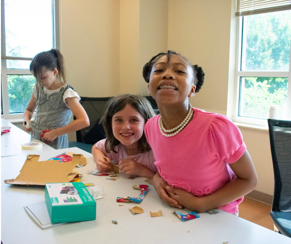 Fourth-grade students smile for a photo while working on a classroom project.
