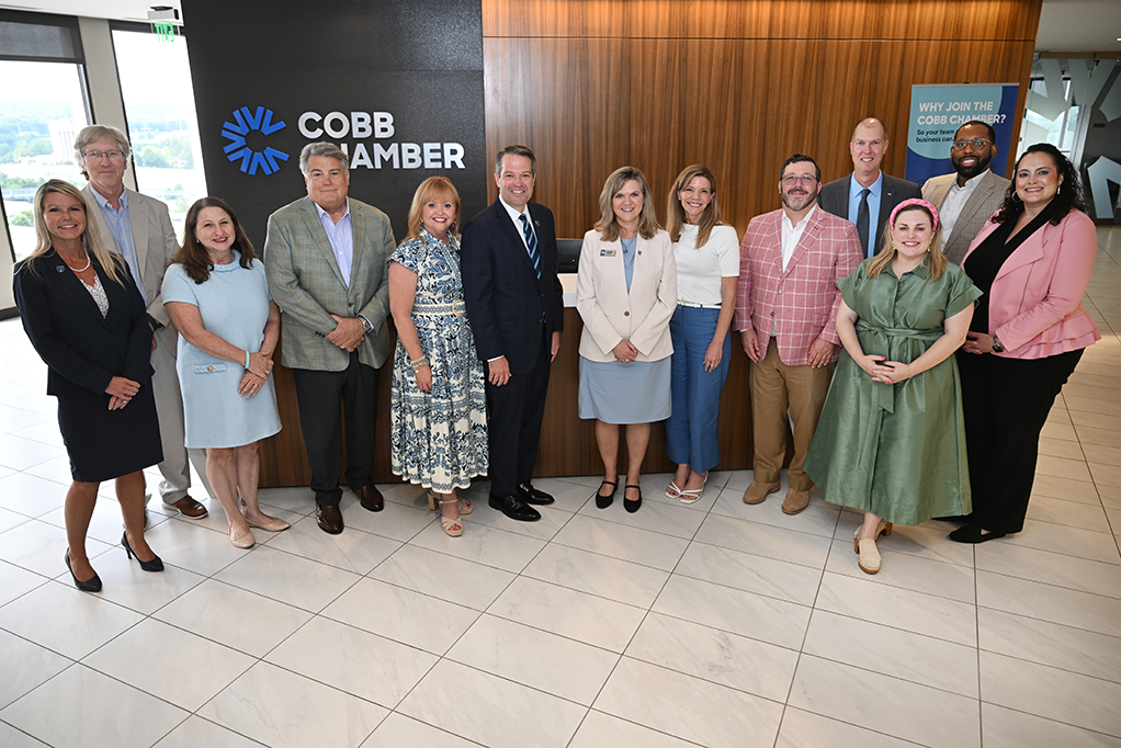 Men and women in business dress in front of large wooden wall
