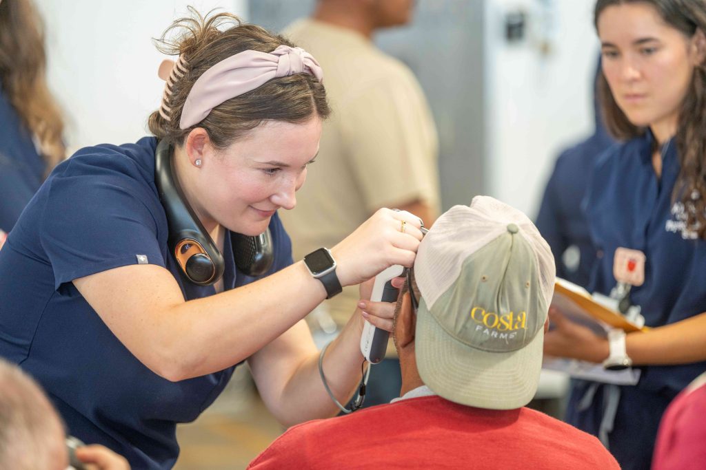Two students work together to evaluate the eyes of a health fair participant.
