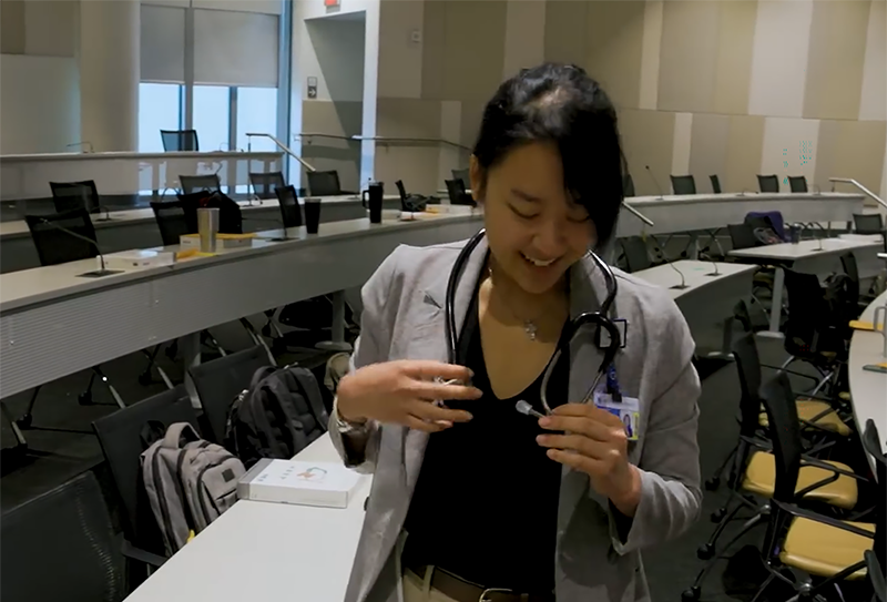 woman holds ends of a stethoscope draped around her neck