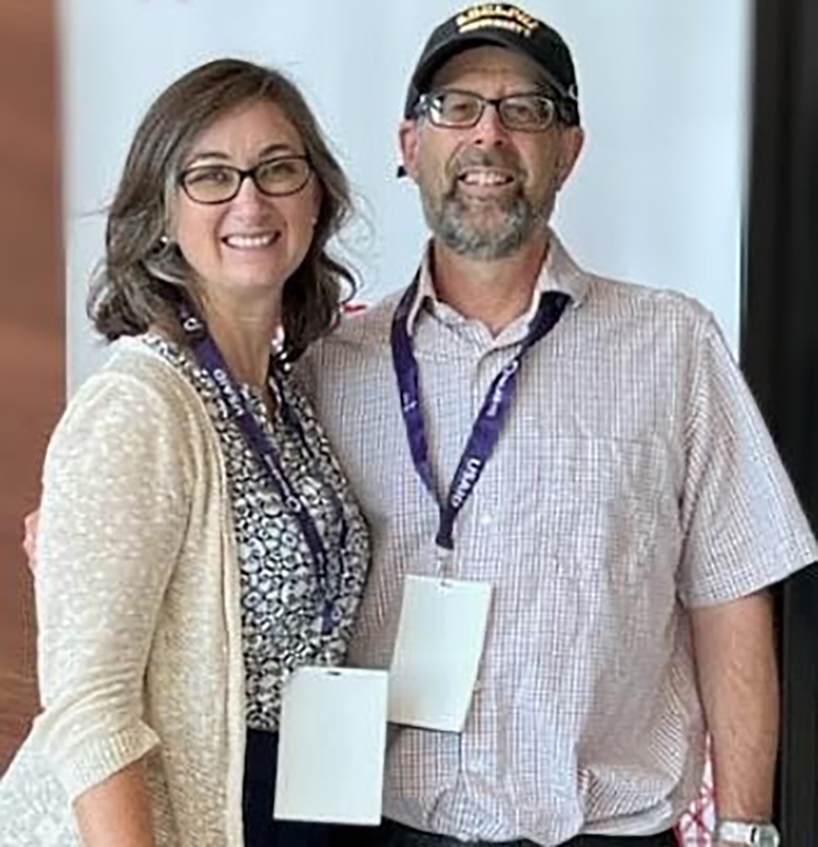 A woman and a man smile at the camera.