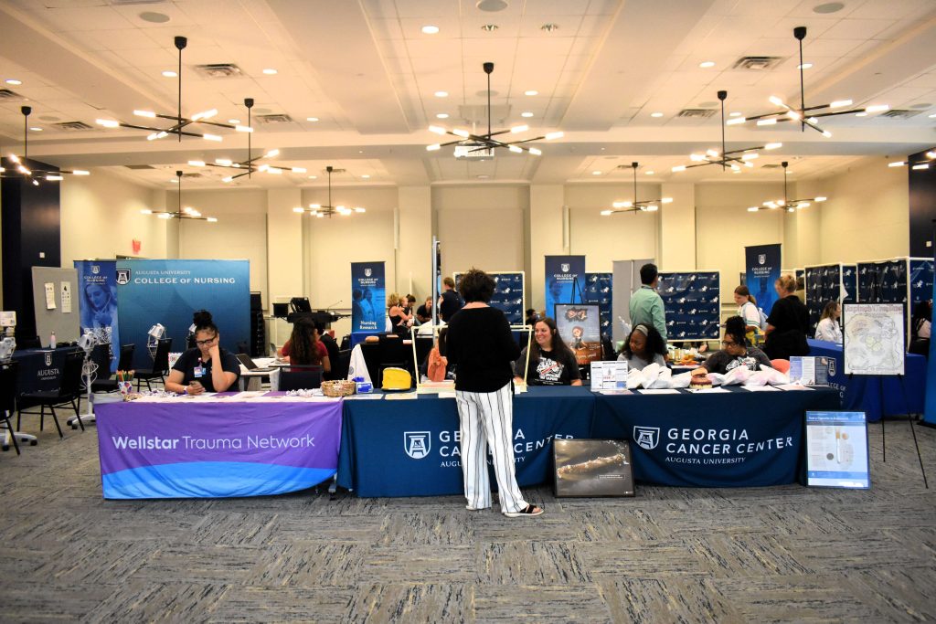 A carpeted ballroom filled with multiple tables and banners to create a health fair.
