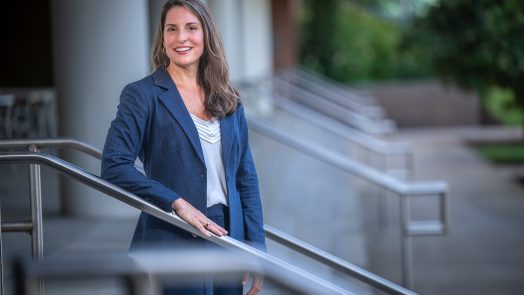 Woman standing in a pant suit on the steps smiling for a photo