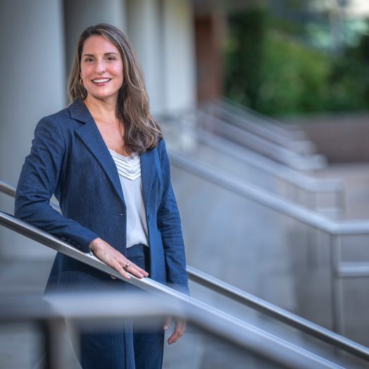Woman standing in a pant suit on the steps smiling for a photo