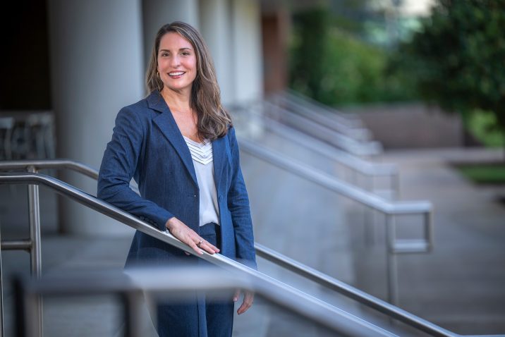 Woman standing in a pant suit on the steps smiling for a photo