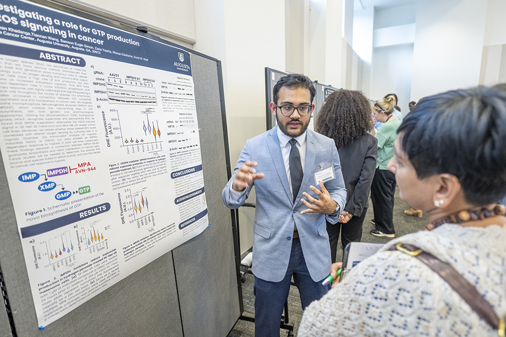 man speaking to a woman while standing next to a poster 