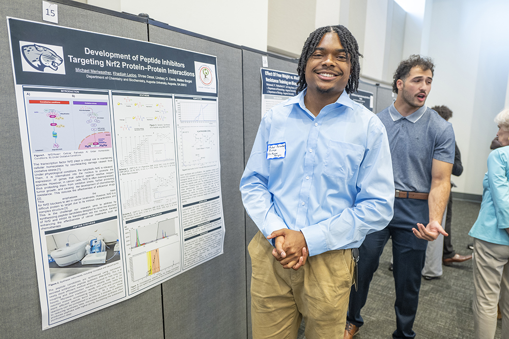 man in a blue shirt standing in front of a poster
