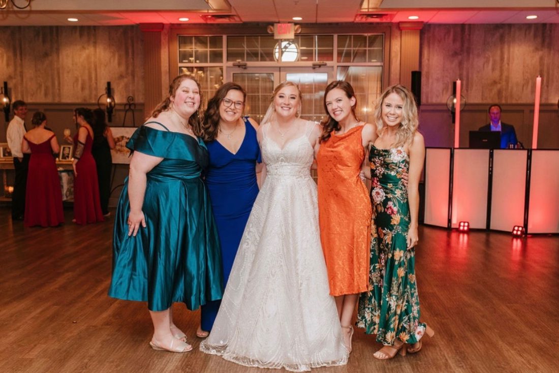Five women smiling at the camera at a wedding.