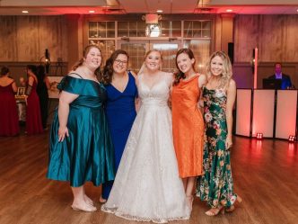 Five women smiling at the camera at a wedding.