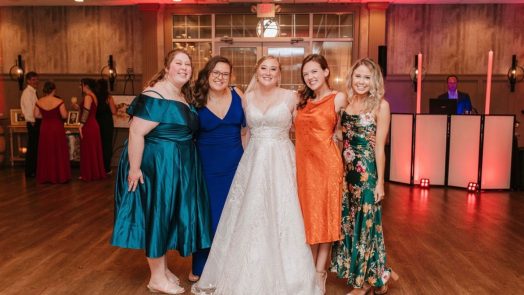 Five women smiling at the camera at a wedding.