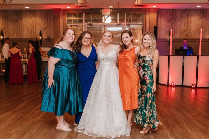 Five women smiling at the camera at a wedding.