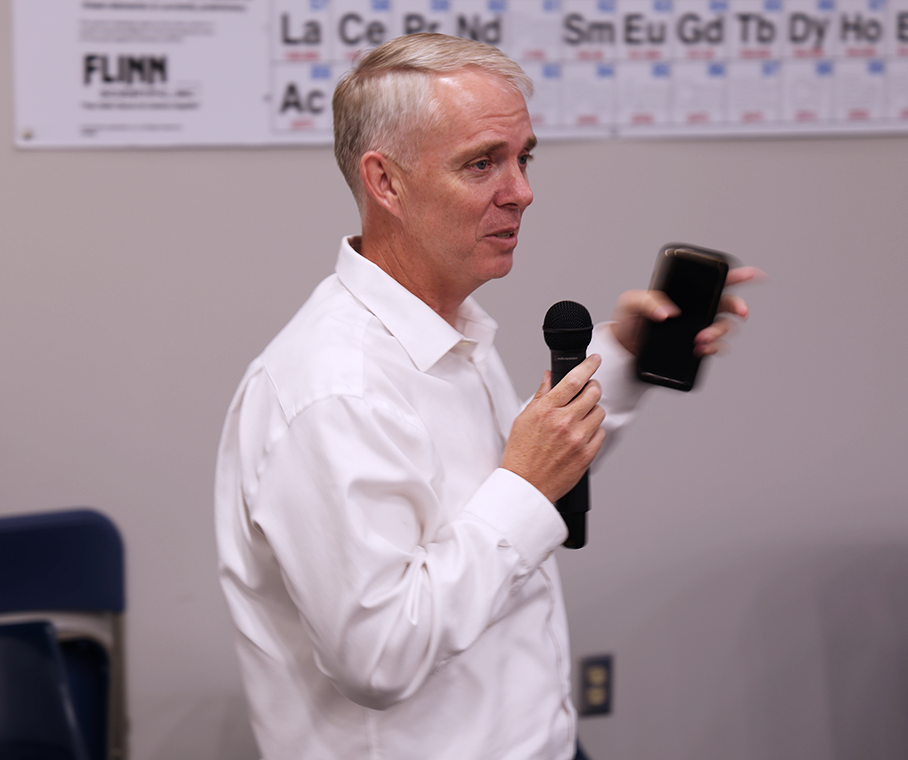 A man speaks into a microphone in an auditorium.