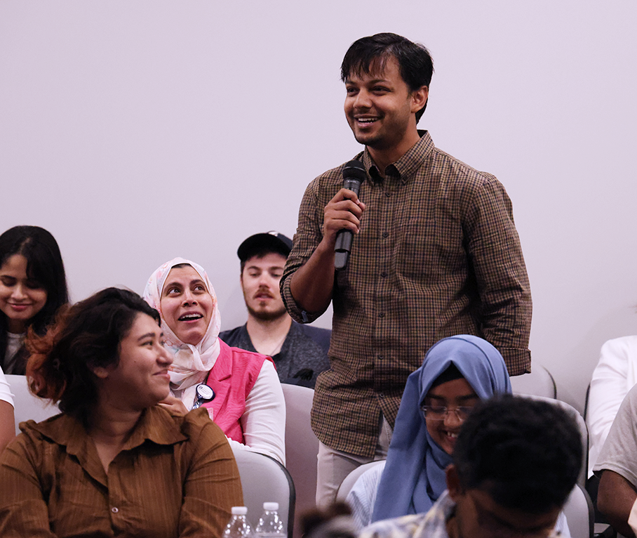 A man speaks into a microphone in an auditorium.