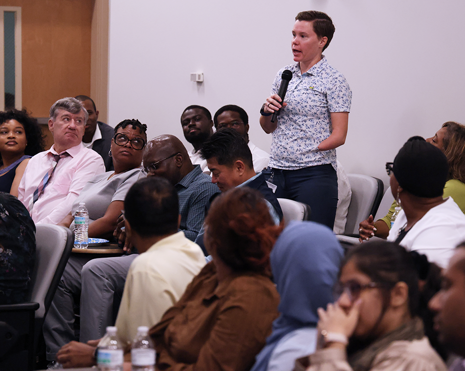 A person speaks into a microphone in an auditorium.