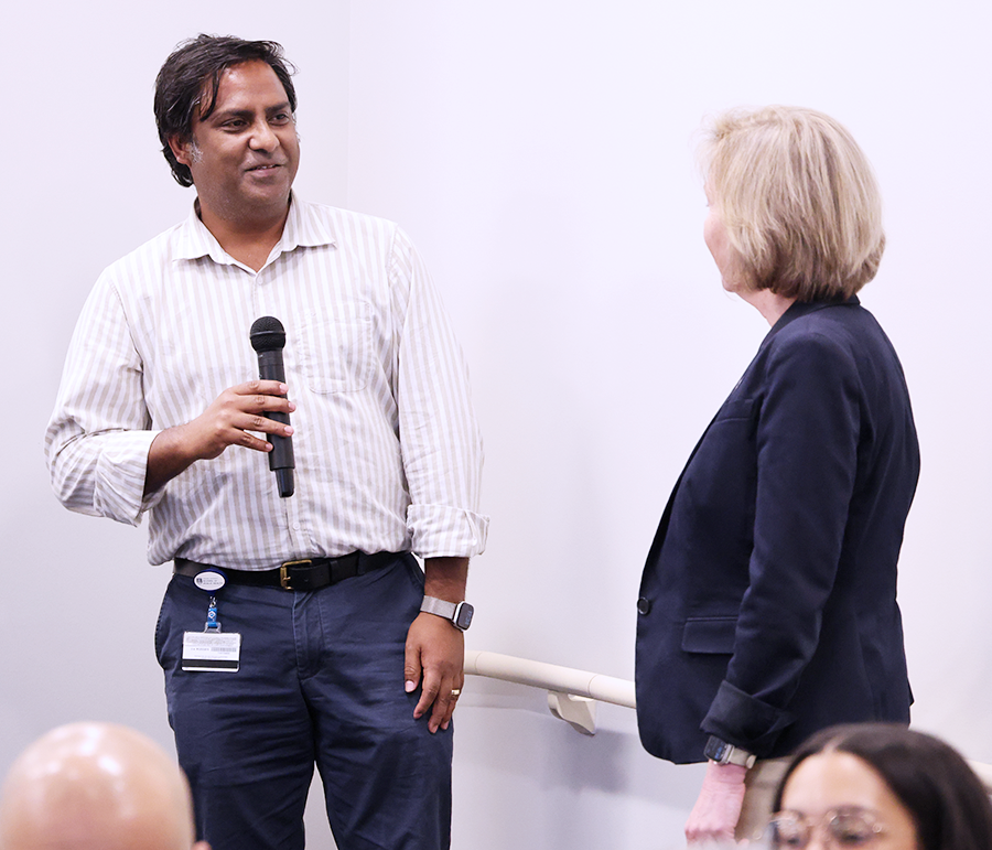 A man holding a microphone looks at a women standing in front of him.