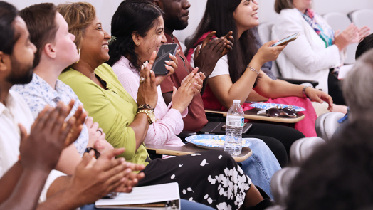 People sit in rows of chairs in an auditorium.