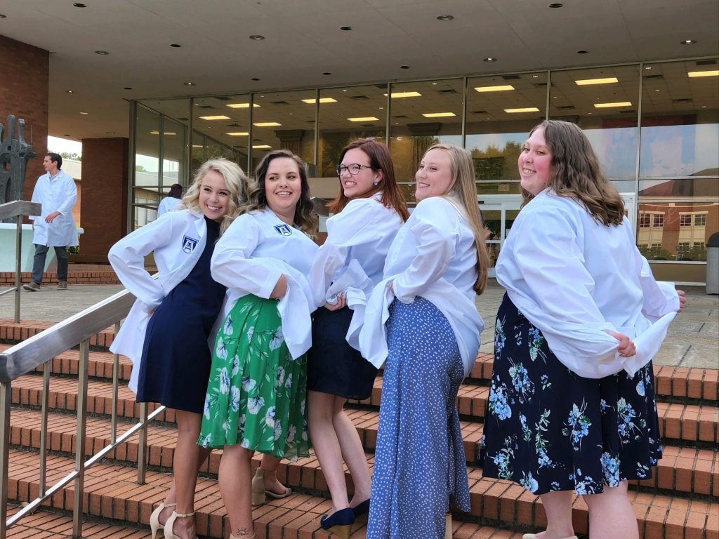 Julie Vincent-Offerdahl, Elisabeth Mellott, Casey Cryan, Nicole Braun, and Emma Heisey pose on a set of stairs wearing their white coats.