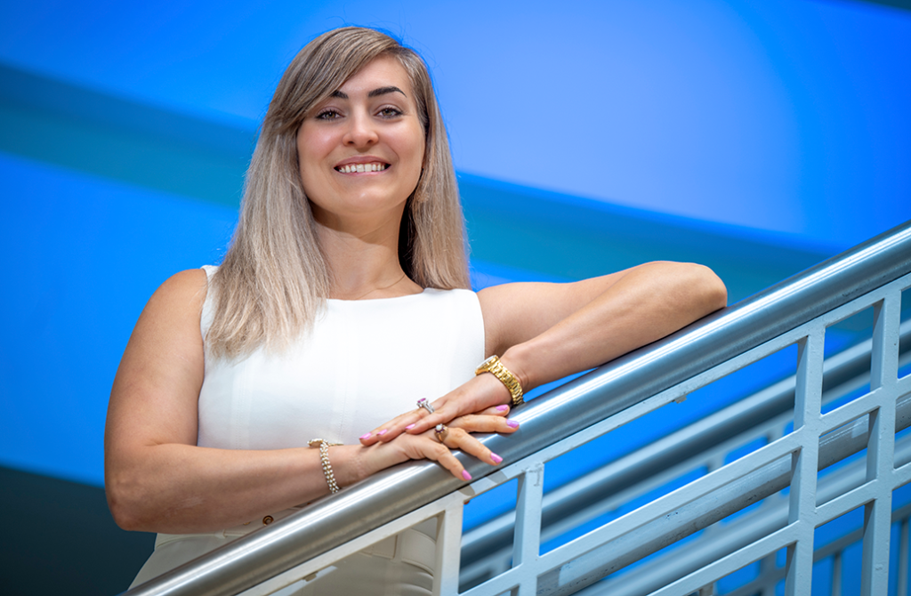 A woman smiles while resting her arms on stair railings.