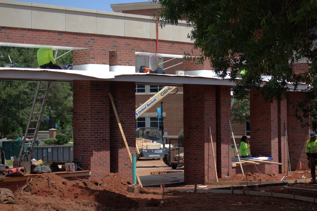 Construction workers building two large brick bus stops.