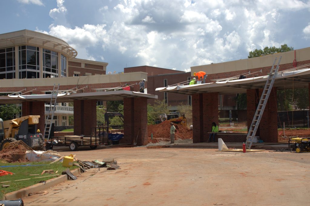 Construction workers building two large brick bus stops.