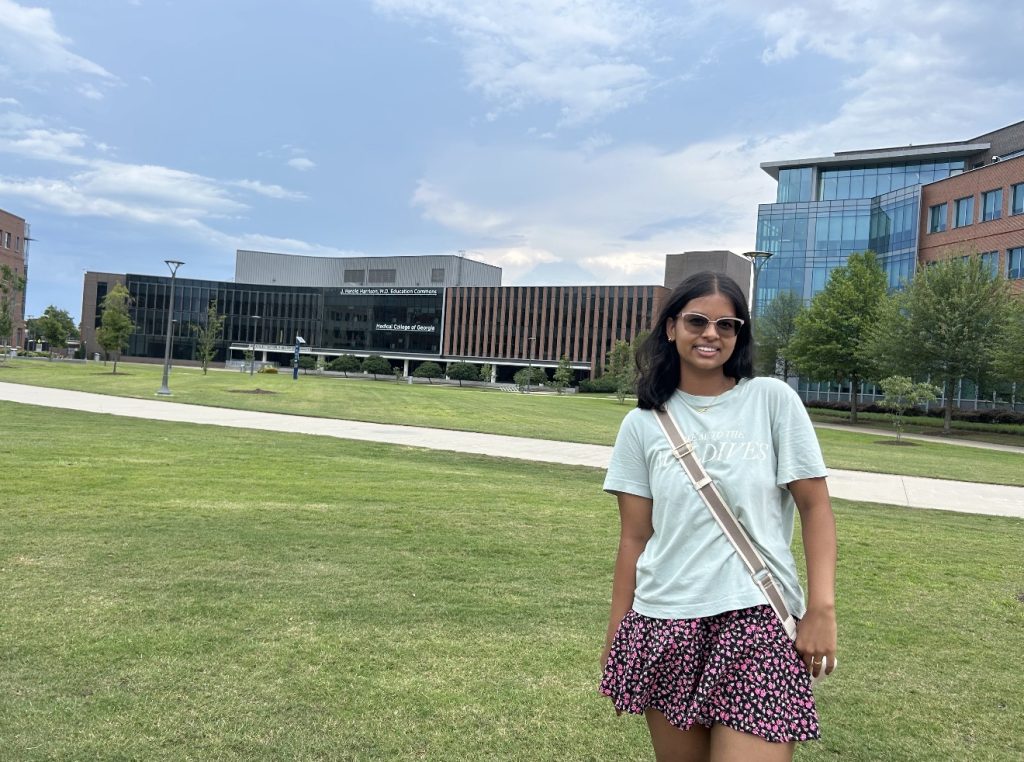 A college-aged woman smiling in front of the Medical College of Georgia.