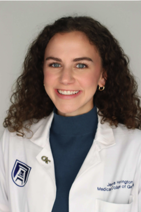 Young woman wearing lab coat facing camera and smiling.
