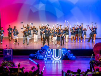students dance on stage with pom poms