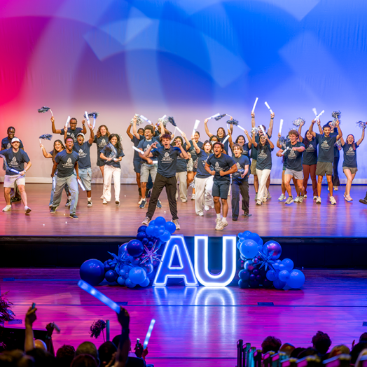 students dance on stage with pom poms