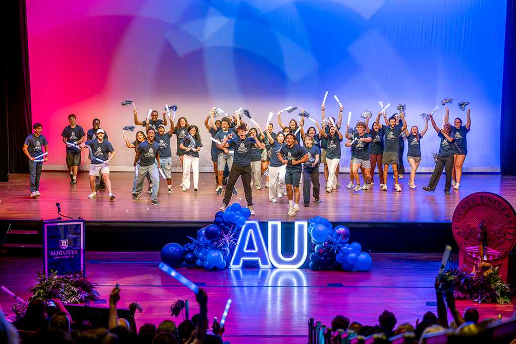 students dance on stage with pom poms