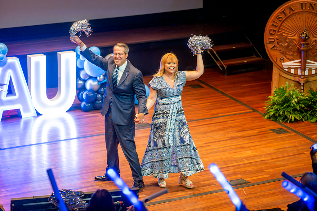 A man and woman on stage holding pom poms.