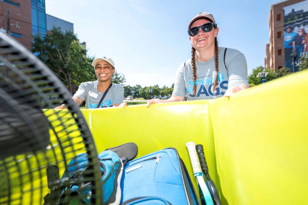 Two women smiling over the side of a move-in cart.