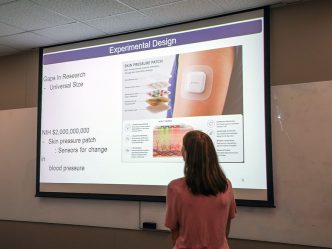 Woman standing in front of a screen that has a graphic on it.