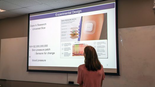Woman standing in front of a screen that has a graphic on it.
