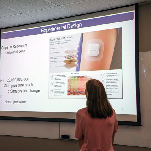 Woman standing in front of a screen that has a graphic on it.