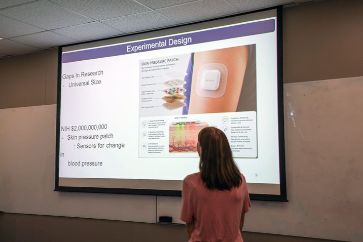 Woman standing in front of a screen that has a graphic on it.
