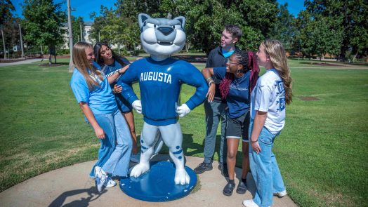 Several college-aged students surrounding the AU mascot Augustus