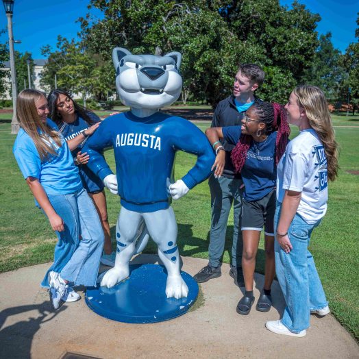 Several college-aged students surrounding the AU mascot Augustus