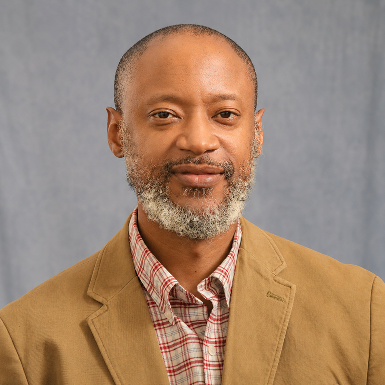 Man poses for photo in front of backdrop.