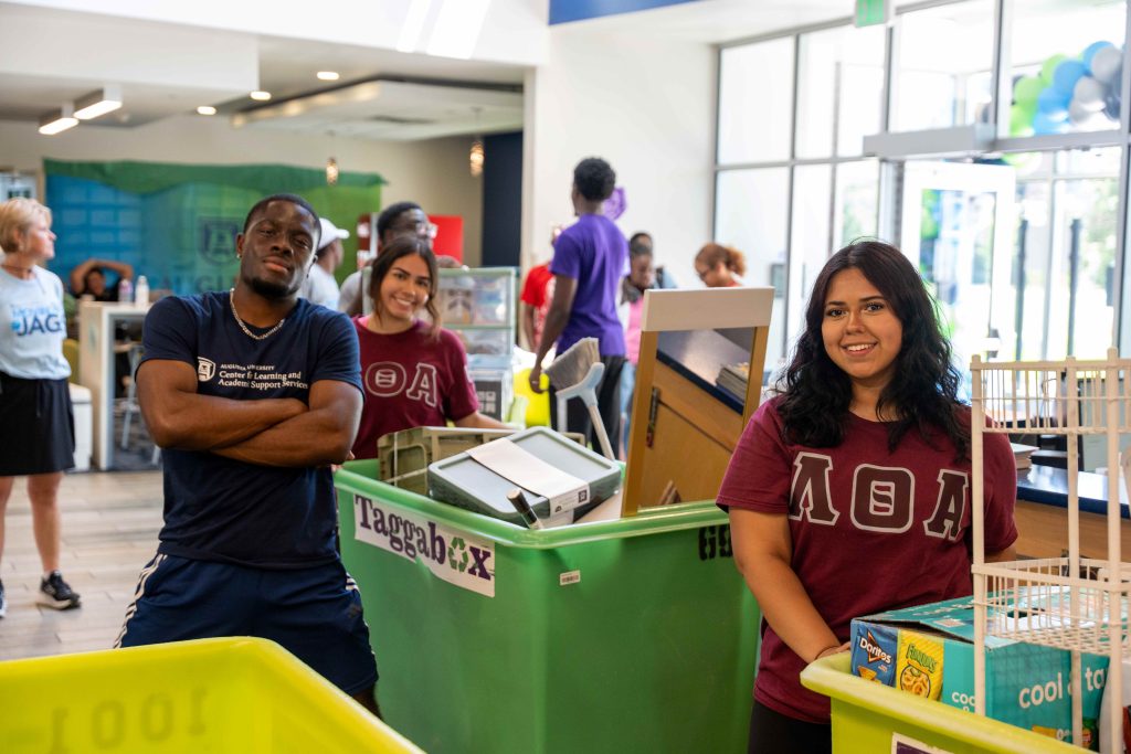 Two women and one man wearing Greek life shirts push move-in carts.