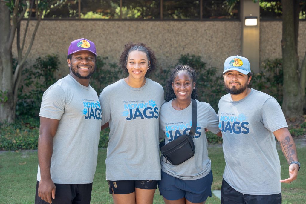 Two men and two women wearing move-in volunteer shirts poses for a photo. 
