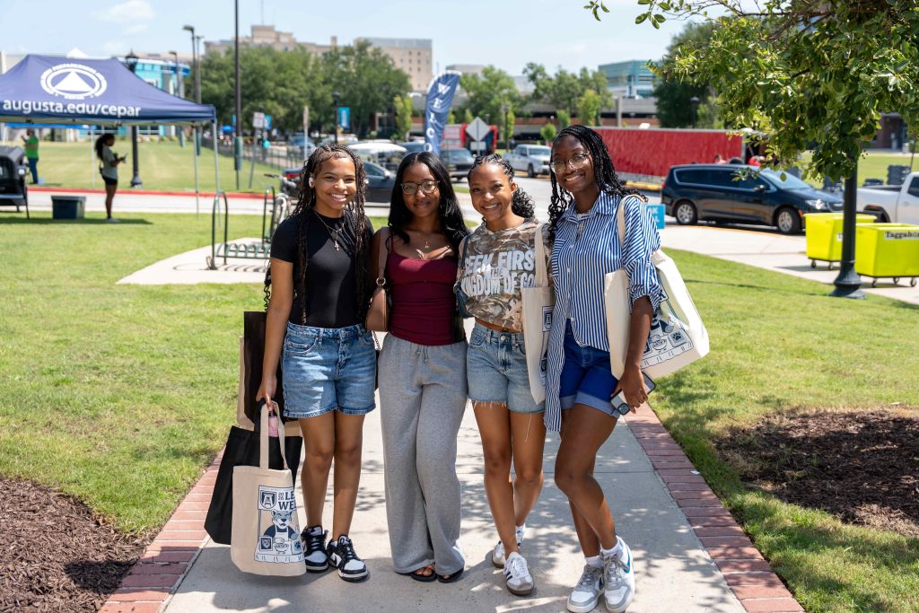 Four college-aged female students standing together while smiling for a photo.