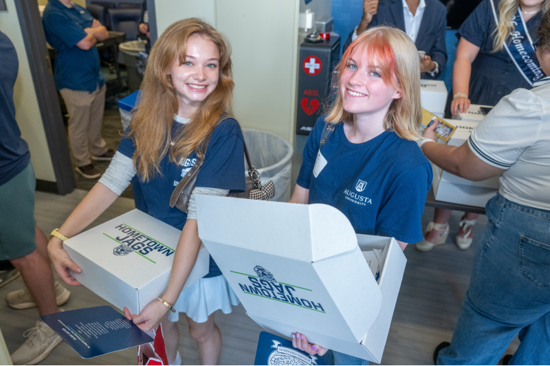 two girls smiling and holding boxes
