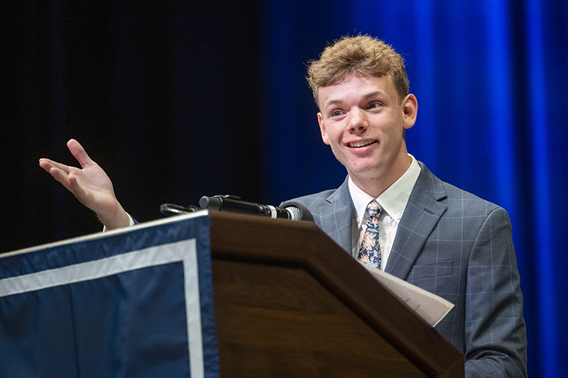 man in a suit and tie standing at a podium