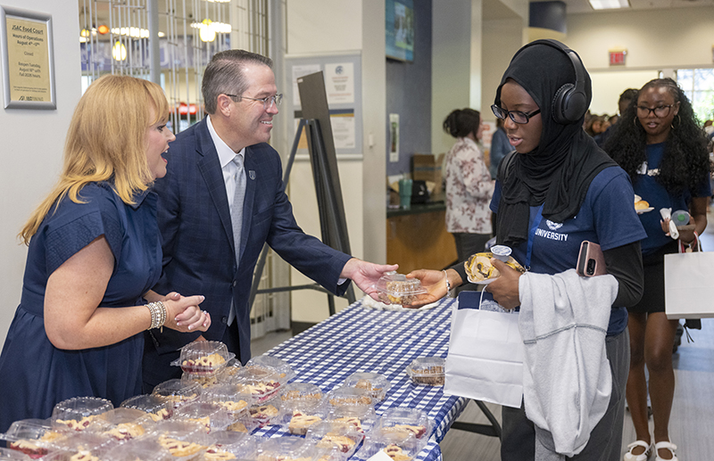 a man and woman handing a piece of pie to a female
