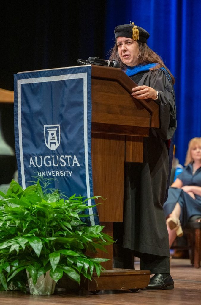 woman wearing a graduation cap and gown standing at a podium