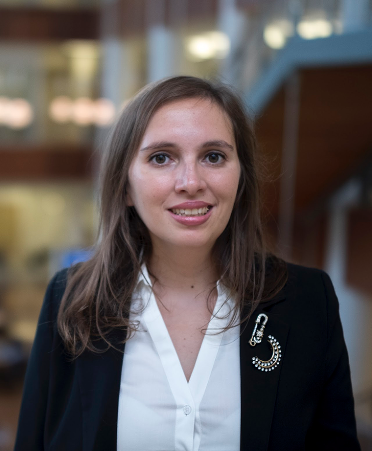 A professionally dressed woman smiles at the camera.